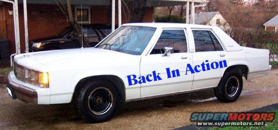 White sedan with blue text 'Back In Action' on the side, parked in a driveway