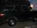 1979 Ford Bronco - Side profile of a dark green 1979 Ford Bronco parked in front of a garage.