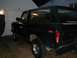1979 Ford Bronco - Rear quarter view of a dark green Ford Bronco parked in front of a garage.
