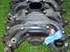 1996 Ford Crown Victoria - A black plastic intake manifold is shown with blue tape covering a sensor, resting on grass.