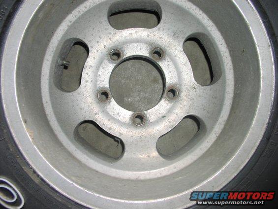 Close-up of a five-lug aluminum wheel with some pitting