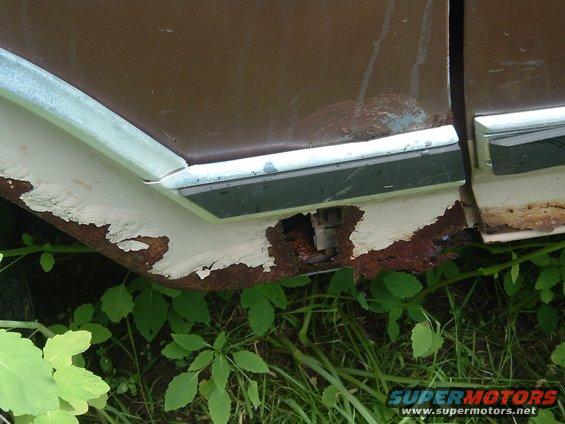 Rusted lower body panel and trim on a brown vehicle