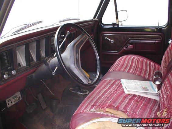 Interior of a 1979 Ford F-Series truck, showing the dashboard, steering wheel, and striped bench seat