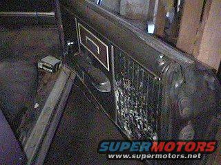 Close-up of a vehicle's side panel with a decorative stripe and a damaged grille