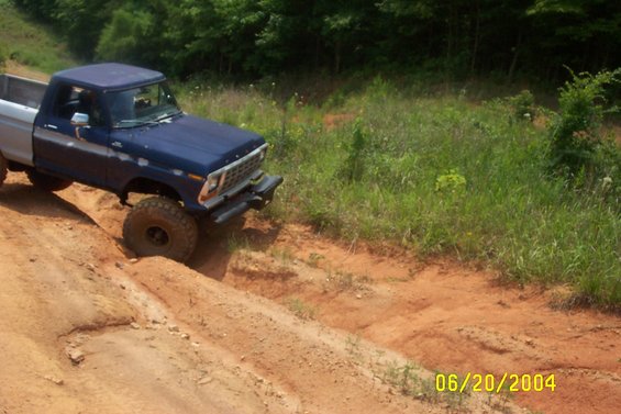 Blue and silver pickup truck with large tires on a dirt hill