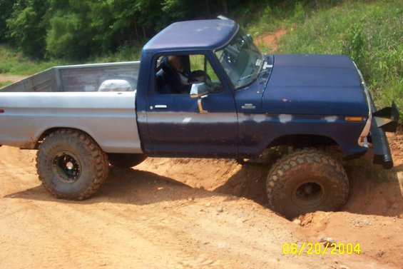 1979 Ford F-150 pickup truck with blue cab and silver bed, driving off-road