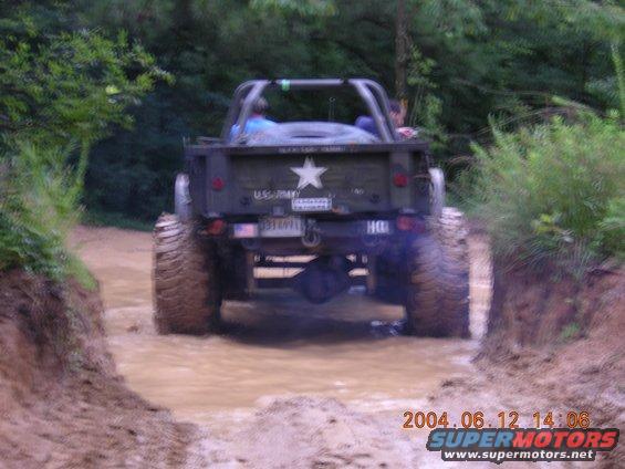 Army truck with large tires driving through mud
