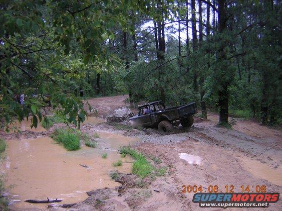 Dark off-road truck stuck in mud on a wooded trail