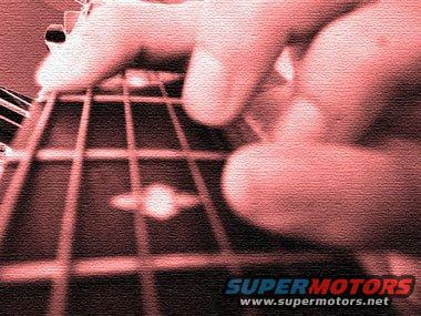 Fingers pressing strings on a guitar fretboard, with SUPERMOTORS.COM watermark