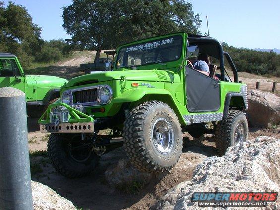 Green Toyota Land Cruiser FJ40 off-roading, another green Jeep nearby