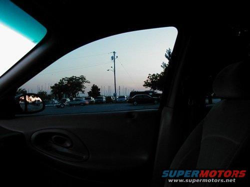 Interior view of a 1997 Ford Taurus showing the driver's side door and window, with a parking lot visible outside