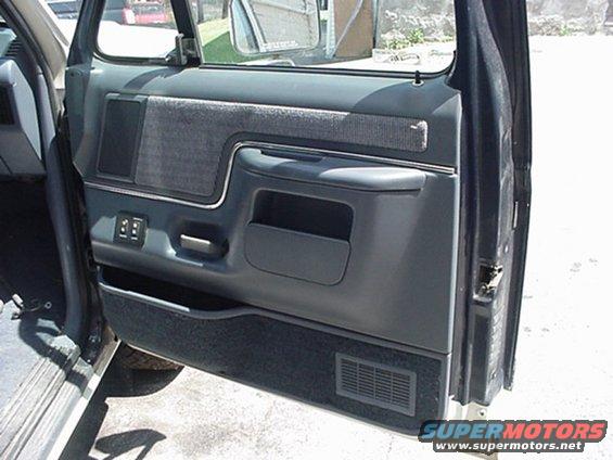 Gray fabric and plastic door panel with armrest and storage pocket. Power window controls visible