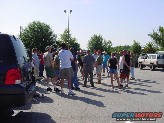 Dark SUV rear, group of people, white Jeep Cherokee