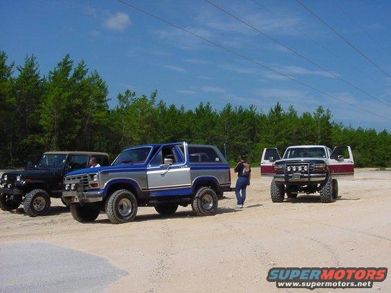 Blue and silver SUV parked on dirt with a Jeep and a pickup truck