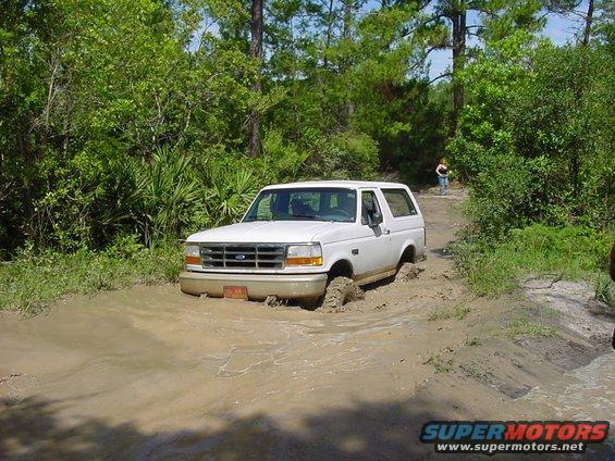 White 1992 Ford Bronco stuck in mud, front 3/4 view