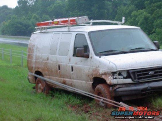 White work van stuck in mud, ladder on roof rack