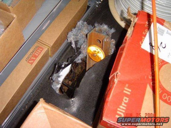 Damaged metal bracket with debris and a small yellow reflector, next to cardboard boxes