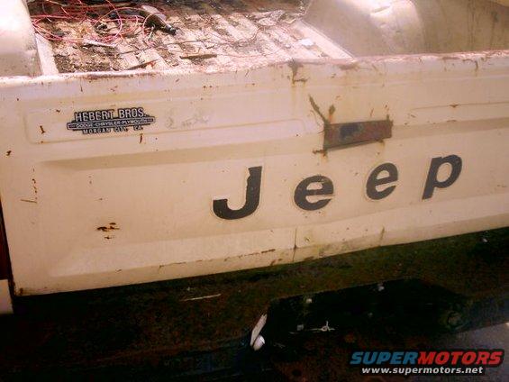 White Jeep pickup truck tailgate with 'Jeep' lettering and 'Hebert Bros.' dealer sticker