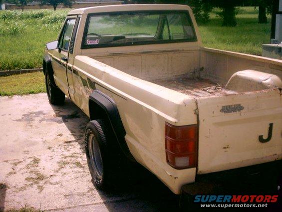 Cream-colored Jeep Comanche pickup truck, rear 3/4 view, showing bed and tailgate