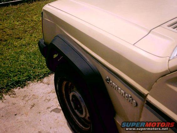 Side view of a tan Jeep Comanche pickup truck, showing front fender and door