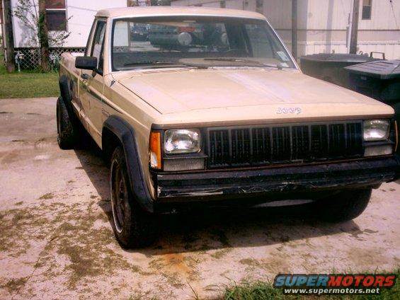 Tan Jeep Comanche pickup truck, 3/4 front view. Visible 'Jeep' badging on grille
