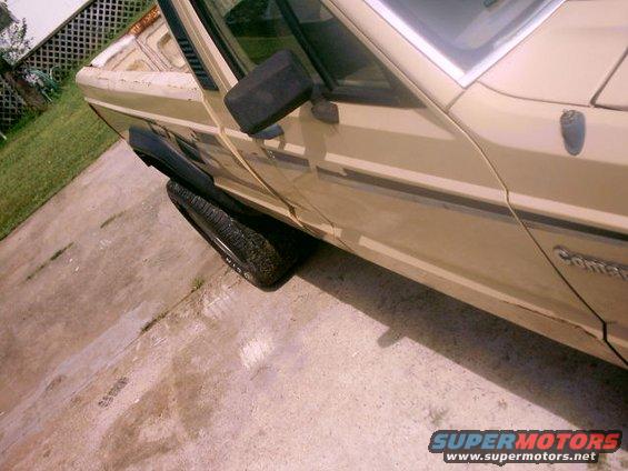 Side view of a tan pickup truck with black fender flares and a black running board. Text on the door reads 'Comanche'