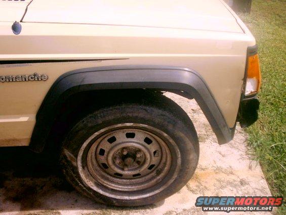 Beige vehicle front fender and wheel with 'Comanche' badge visible