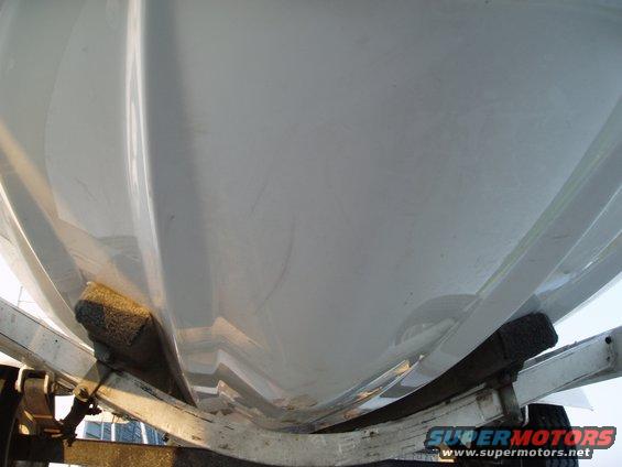 Underside of a white boat hull resting on a trailer with black bunks