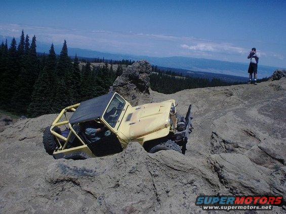 Yellow off-road vehicle with roll cage on rocky terrain