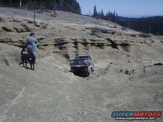 Dark blue pickup truck navigating a steep, rocky incline