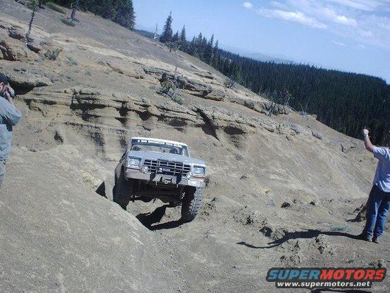 1978 Ford Bronco climbing a steep, rocky hill with two people watching
