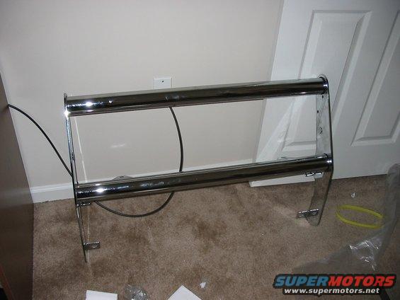 Chrome bull bar with two horizontal tubes and vertical supports, resting on carpet
