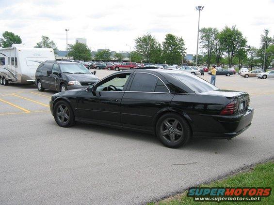 Black sedan towing a trailer, side view