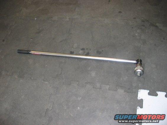 Torque wrench with a socket attached, lying on a gray interlocking floor mat