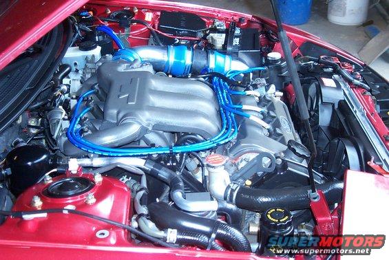 Engine bay with blue spark plug wires and silver intake piping