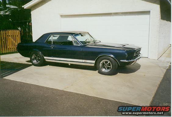 Dark blue 1967 Ford Mustang coupe with chrome trim and racing wheels parked in a driveway