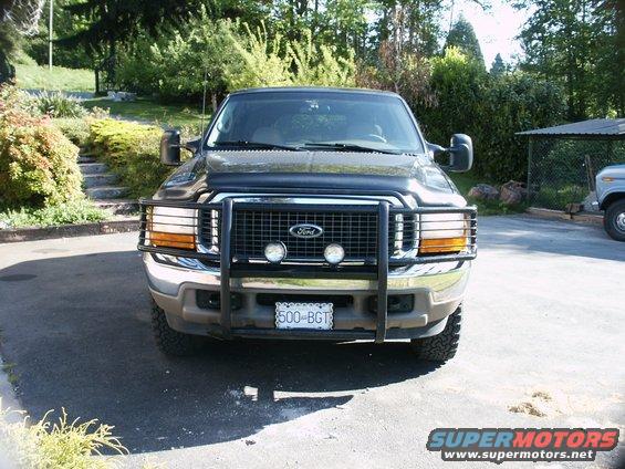 Black Ford Excursion with a brush guard and fog lights, front view