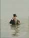 1998 Ford Crown Victoria - A man dressed in formal attire stands waist-deep in the water, adjusting his eyewear.
