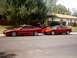 1996 Ford Probe - Two red Ford Probe cars are parked side-by-side on a street in front of a house.