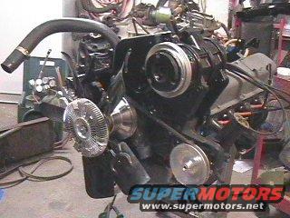 Engine assembly with fan, pulleys, and hoses. Supermotors.net logo visible