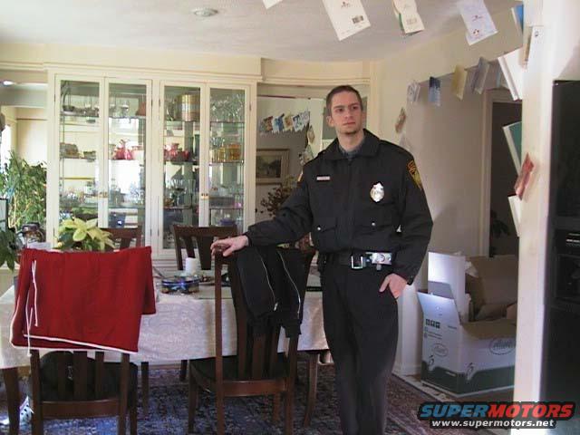 Man in uniform standing in a dining room with a china cabinet