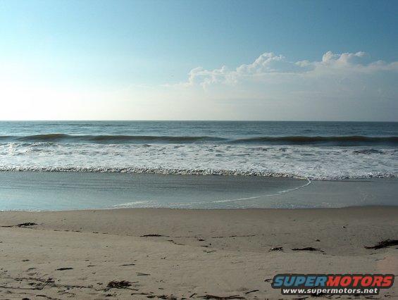 Beach with waves and clouds, "SUPERMOTORS www.supermotors.net" logo in lower right
