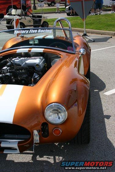 Orange sports car with white stripes, engine exposed, front view