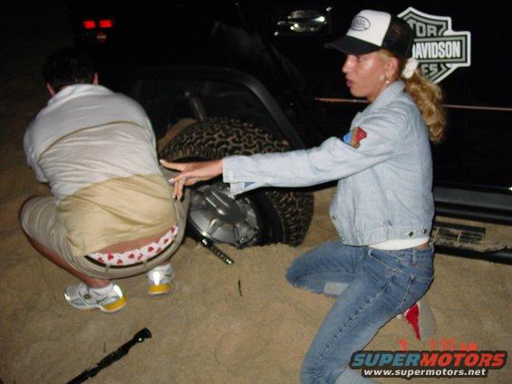 People examining a stuck vehicle with a Harley Davidson logo on the side