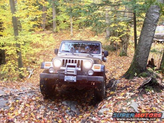 Tan Jeep Wrangler on rocky trail with fall foliage
