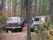 1980 Ford F-100 - Two off-road vehicles are parked on a trail in a wooded area during autumn.