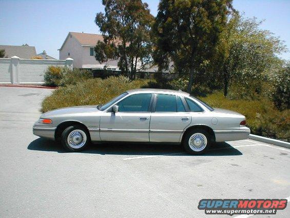 Silver sedan parked on asphalt, side view. Tinted windows, chrome wheels