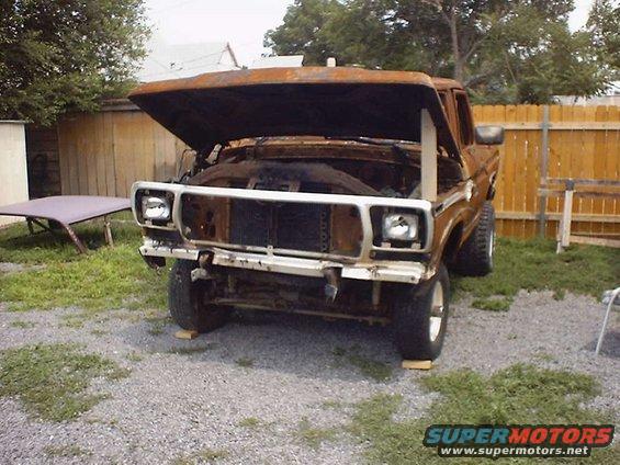Front view of rusty brown SUV with hood open, showing engine bay