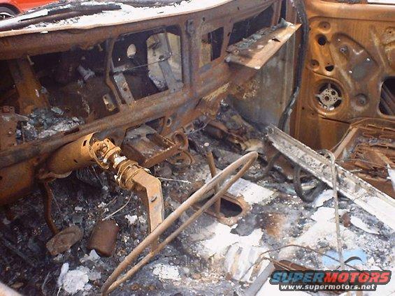 Burned-out vehicle interior with damaged dashboard and steering column