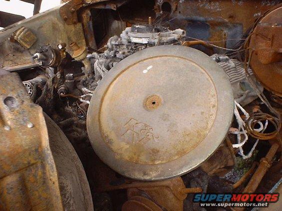 Engine bay of a burnt vehicle, showing the carburetor and air cleaner